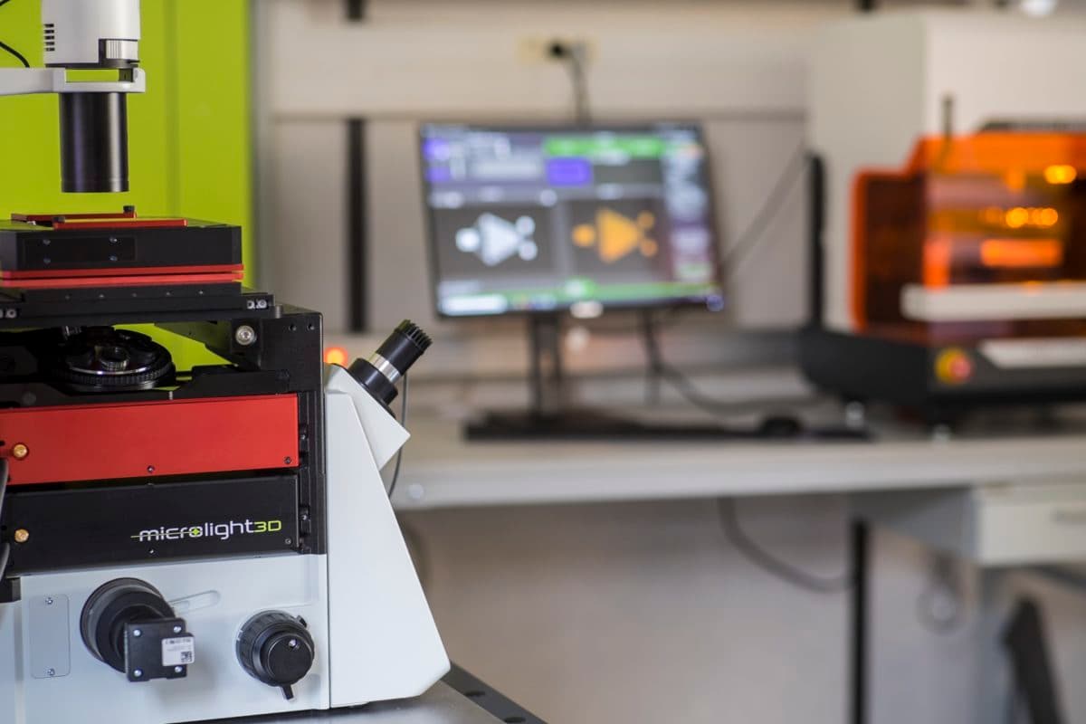 Photo of both our products taken in our lab, with a monitor showing a printing process